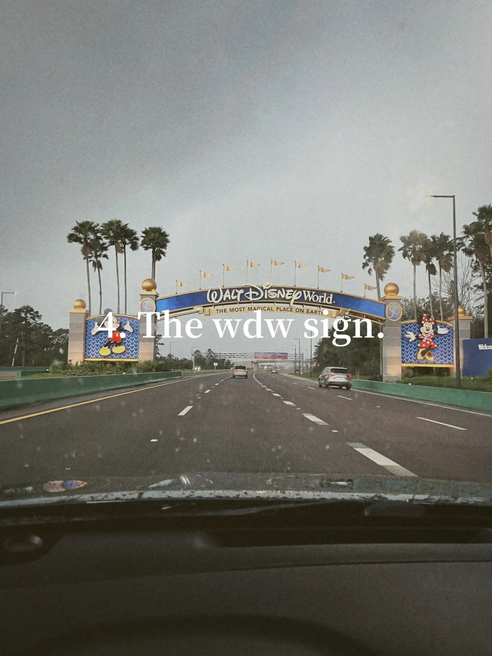  A car is driving down a highway with a sign that says "The wdw sign".