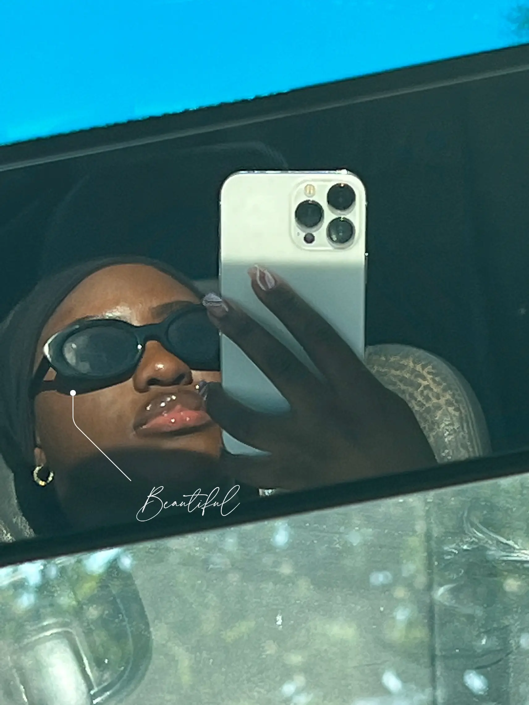  A woman wearing sunglasses and a black headband is taking a selfie in the mirror.
