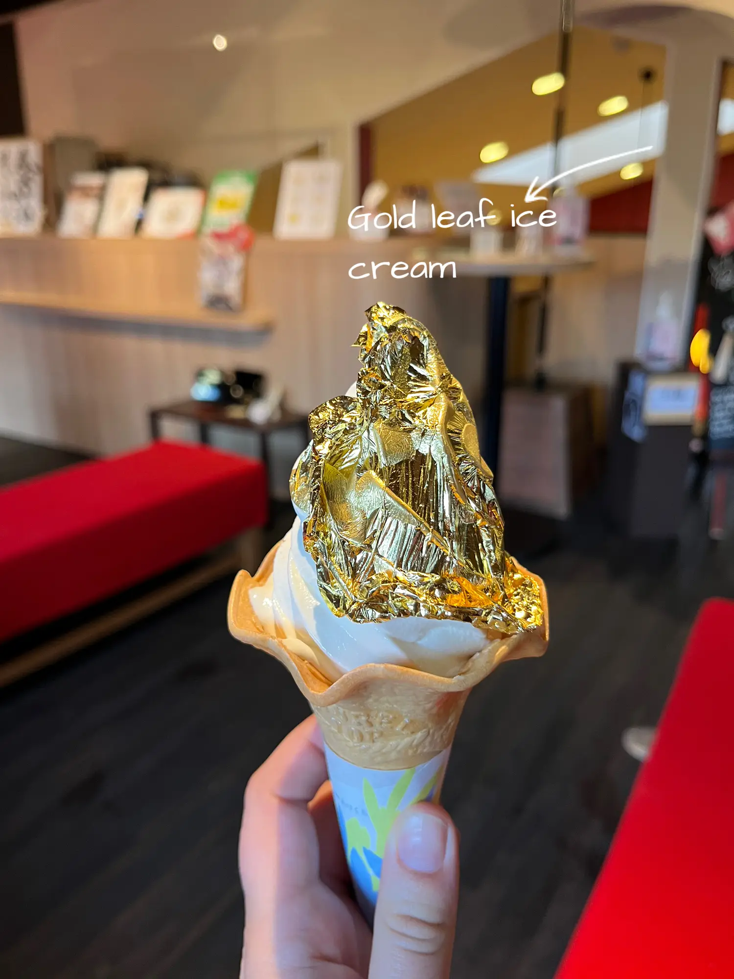  A person is holding a large ice cream cone with a gold leaf on it.