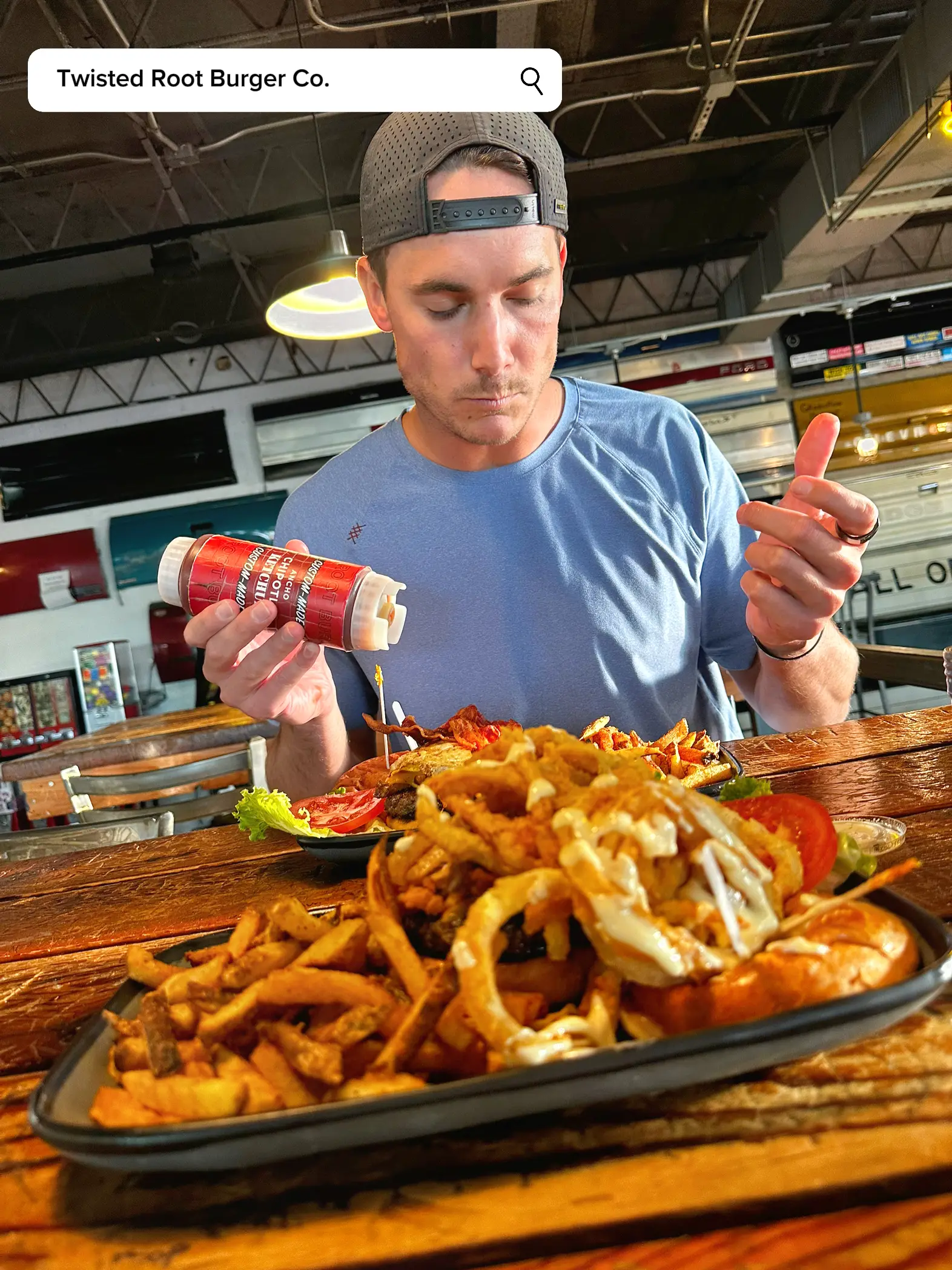  A man is holding a plate with a cheesy fries and a burger.
