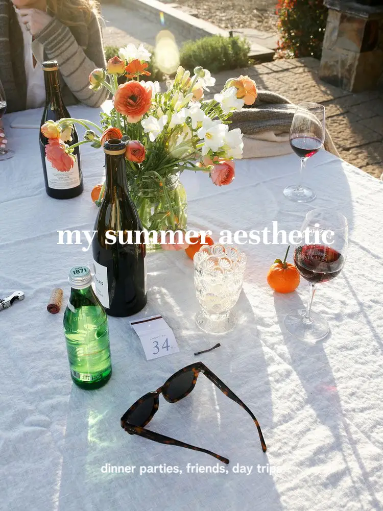  A table with a vase of flowers, a glass of wine, and a bottle of water.