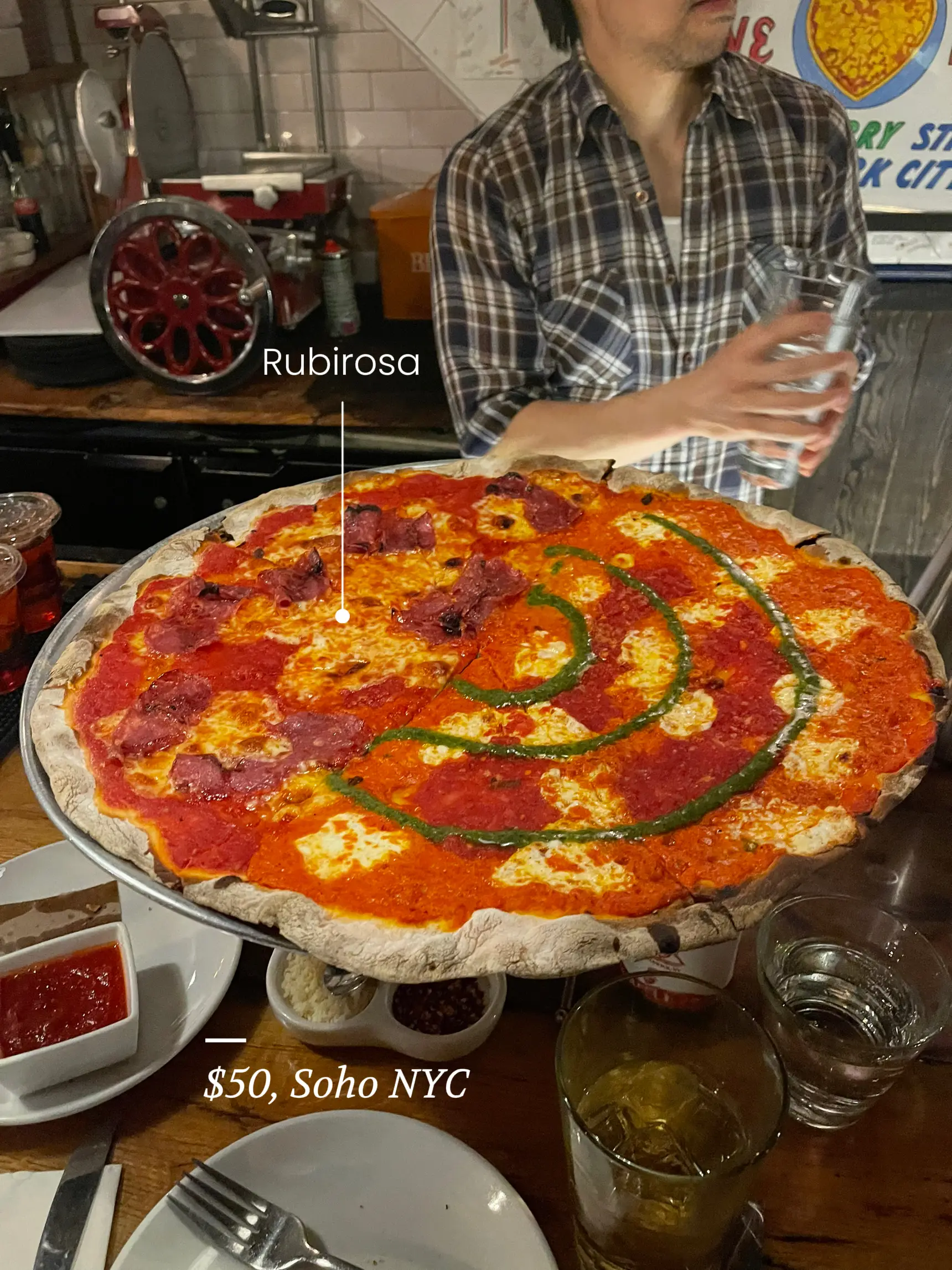  A large pizza with a lot of toppings is sitting on a table. The pizza is covered in cheese and has a price of $50.