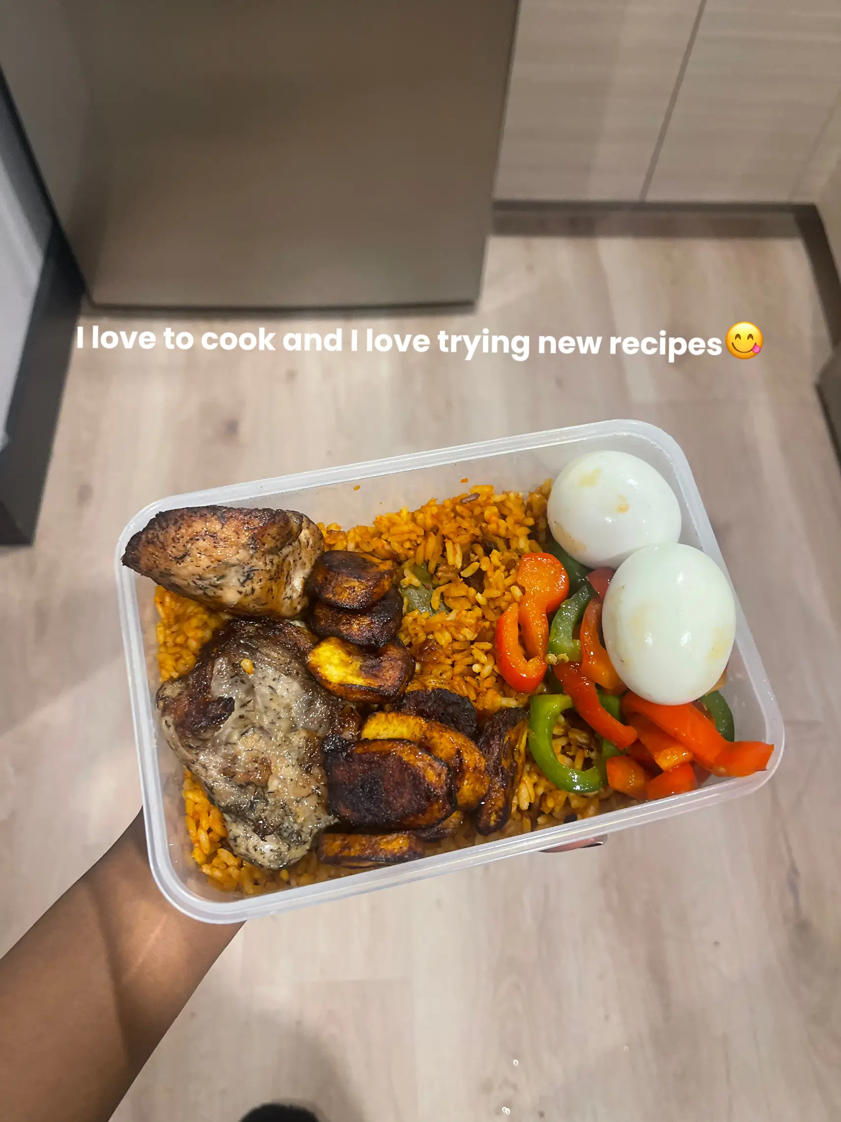  A person is holding a container of food with a rice dish and a meat dish. The container is described as having a rice dish and a meat dish. The person holding the container is also