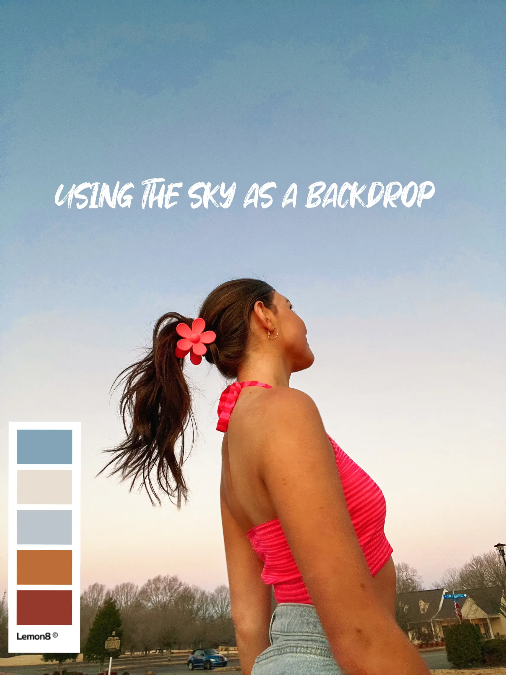  A woman wearing a pink shirt and black pants is standing in front of a blue sky.