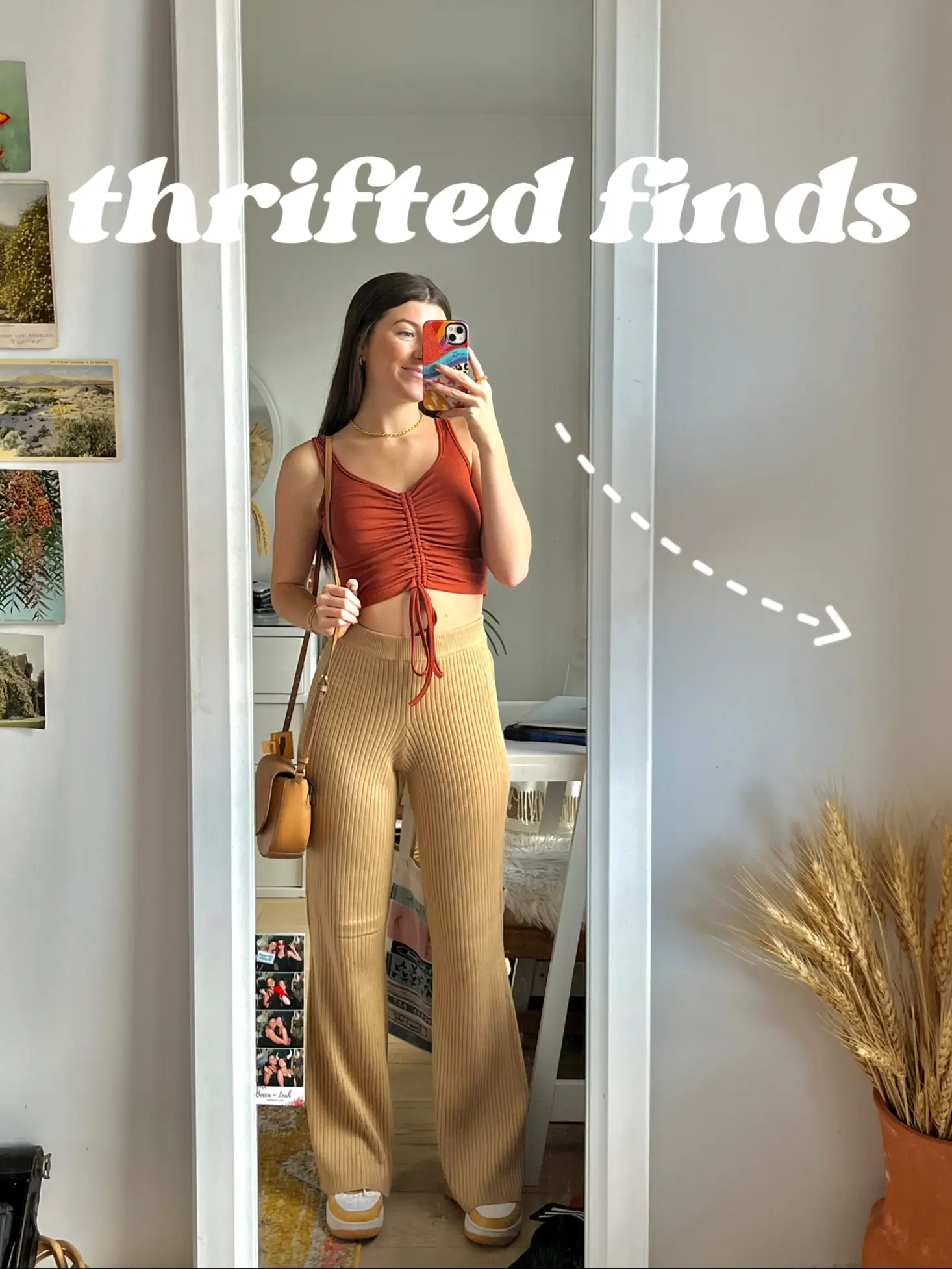  A woman in a red top and blue pants is taking a selfie in a mirror.