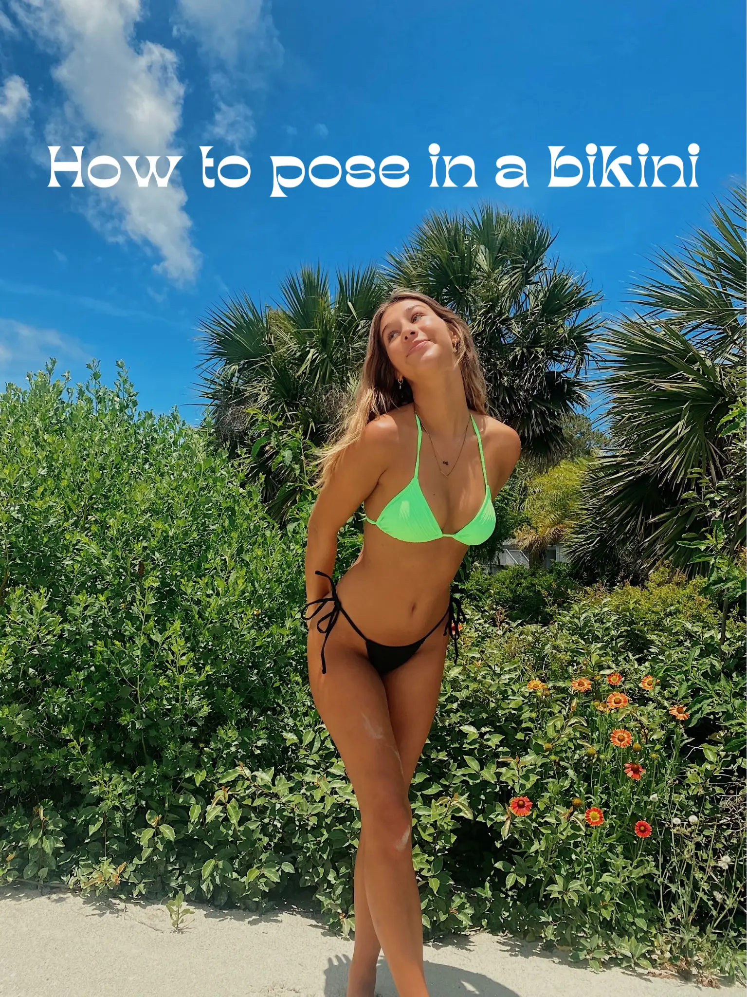  A woman in a bikini is posing in front of a bush.