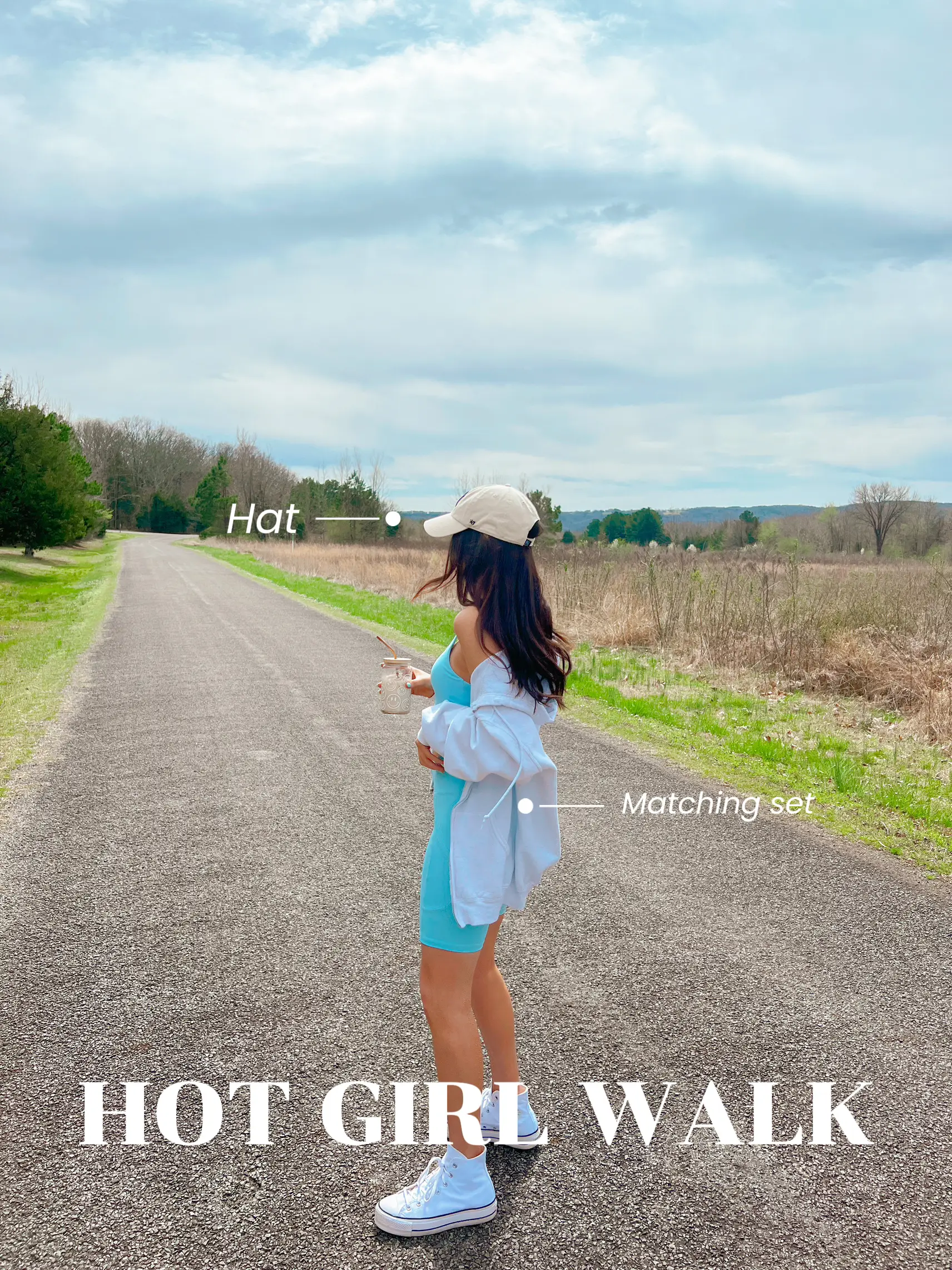  A woman wearing a white hat and a white shirt is walking down a road.