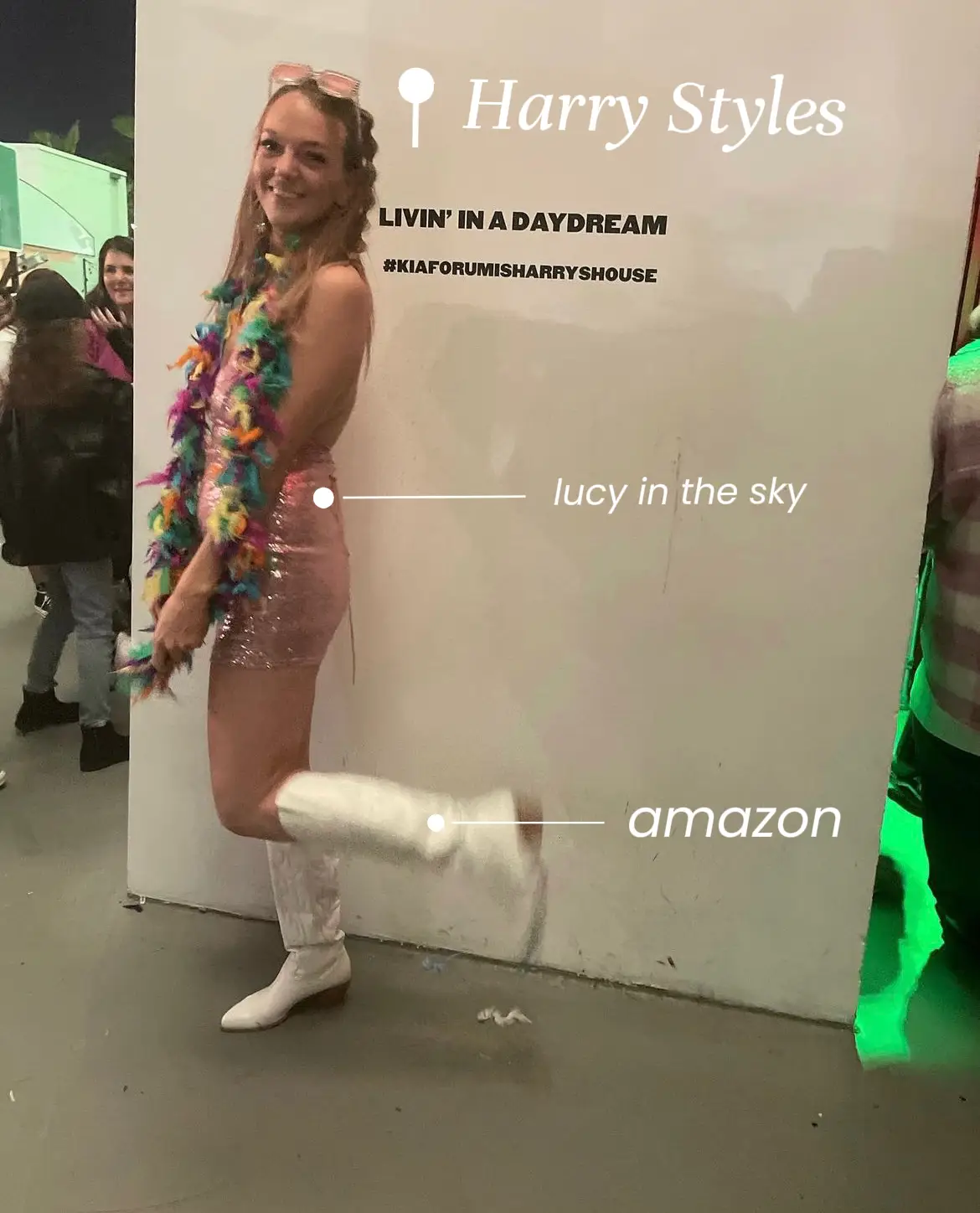  A woman wearing a colorful skirt and white boots is standing in front of a wall with a sign that says "Lucy in the sky". She is smiling and appears to be enjoying herself.