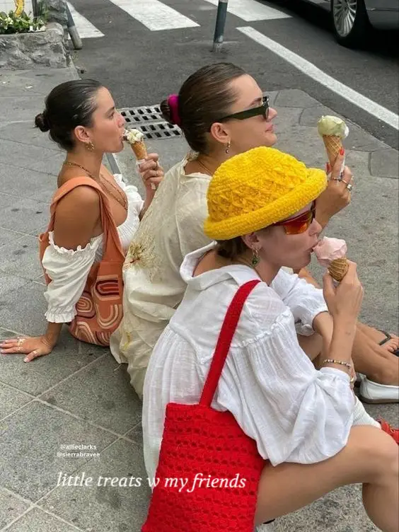  Three women are sitting on the ground, eating ice cream.