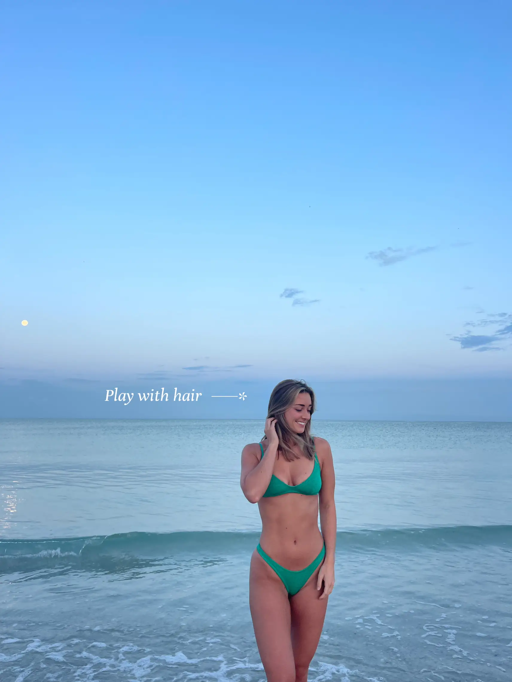  A woman in a green bikini is standing in the ocean.