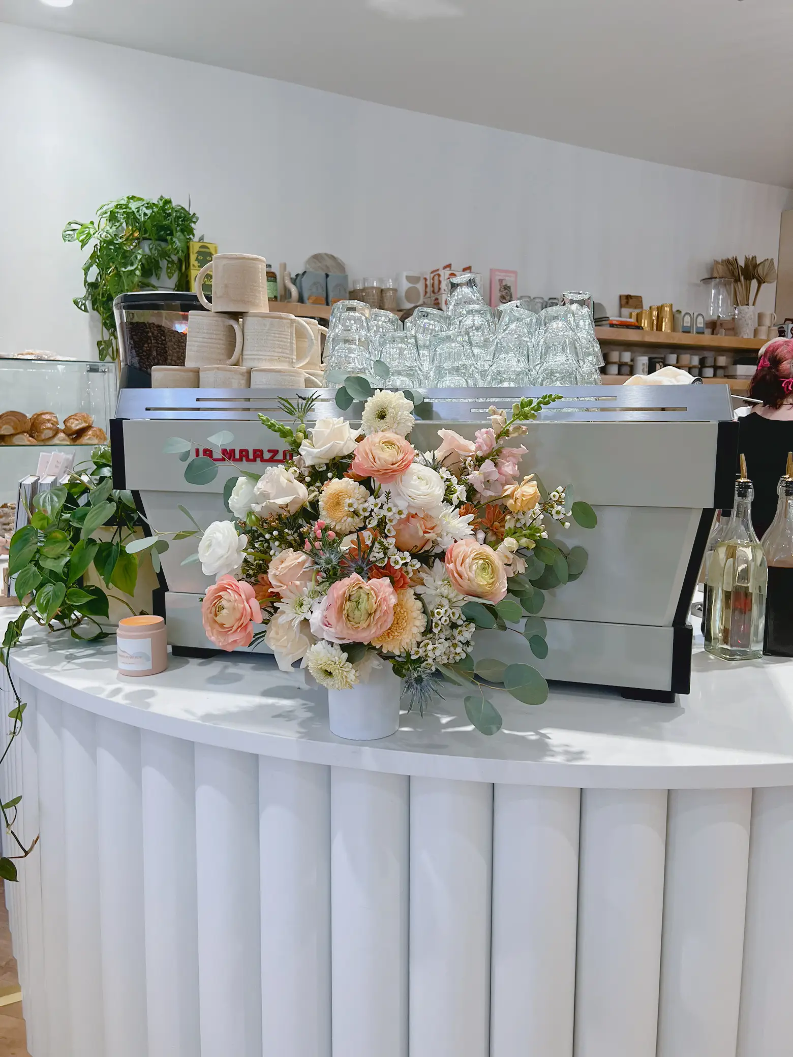  A coffee shop with a counter and a vase of flowers on it.