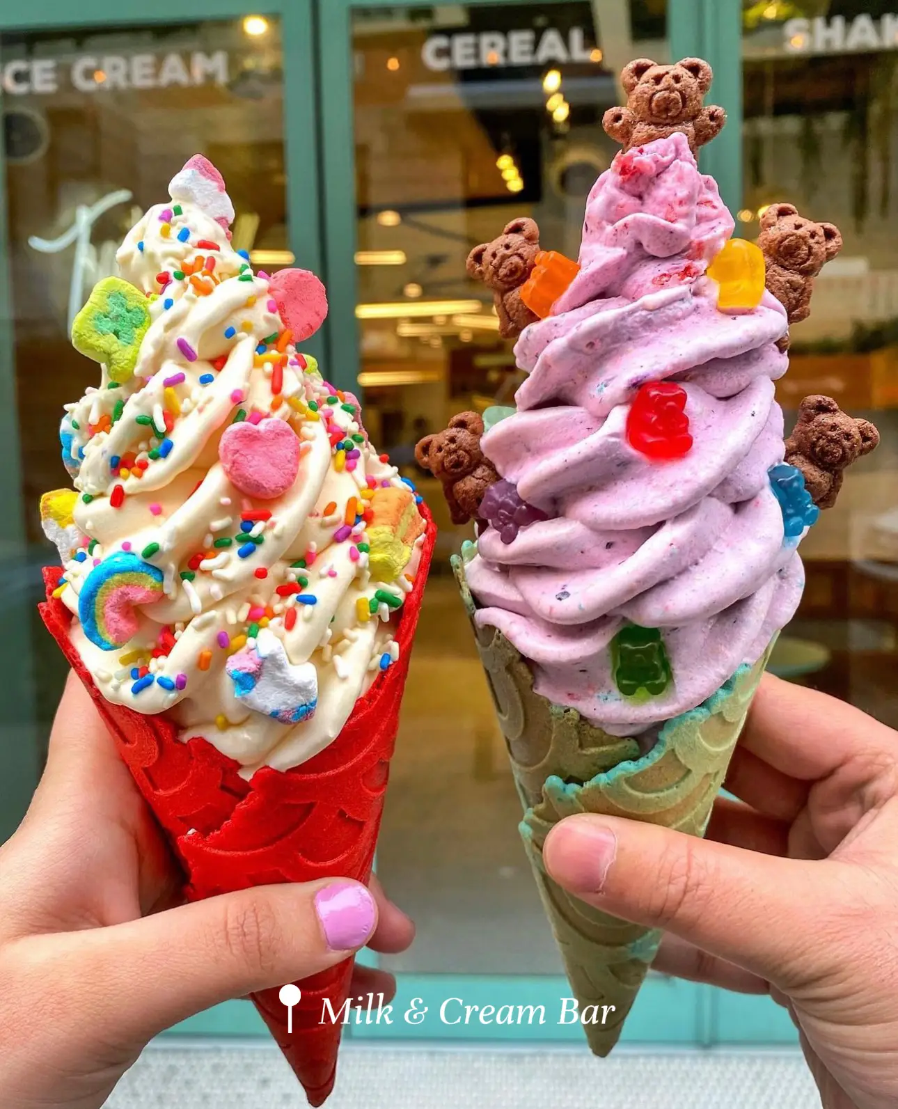  Two pink frosted ice cream cones with sprinkles.