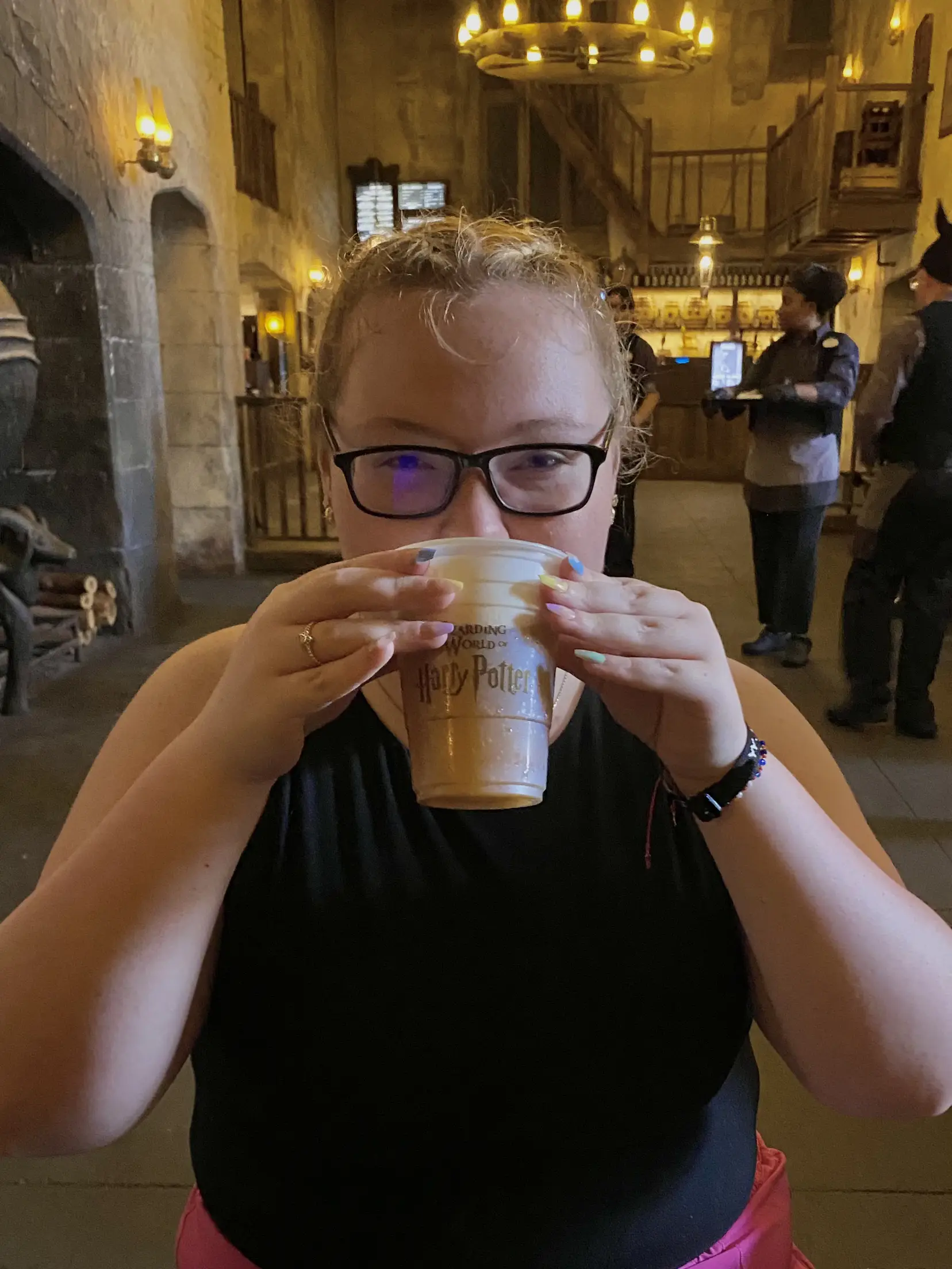  A woman in glasses is drinking from a mug with the words "Daily Potter" written on it.
