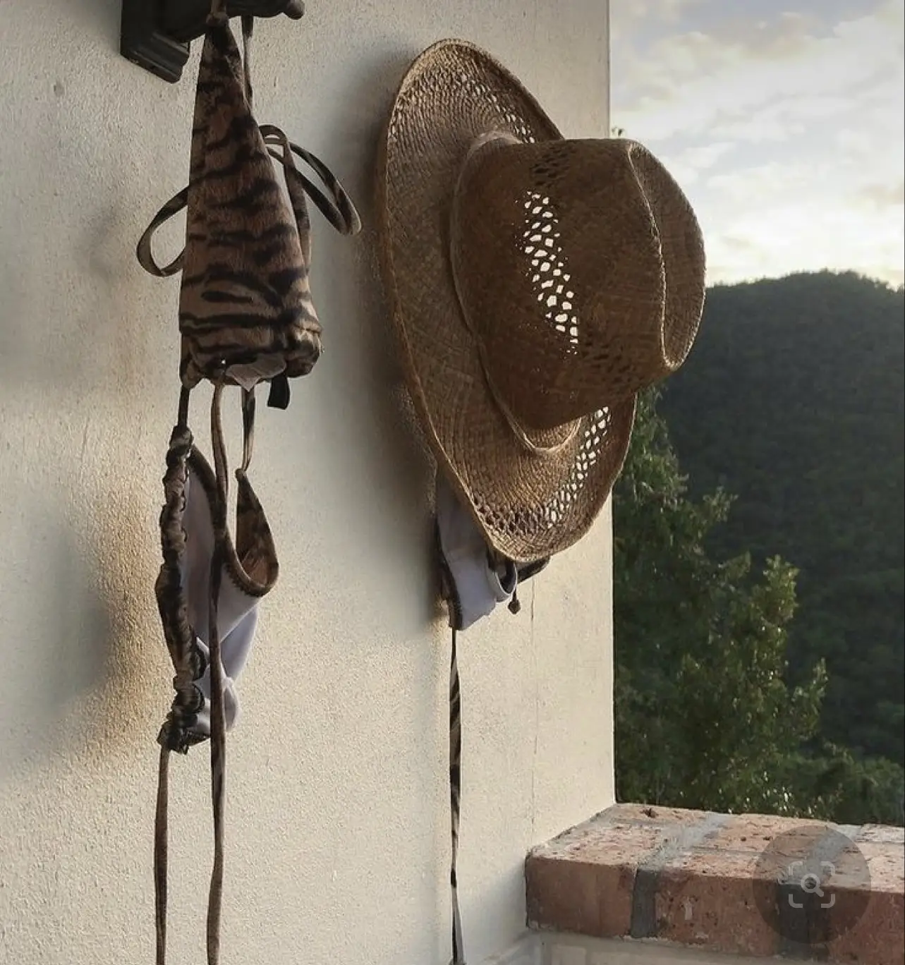  A white hat with a leopard print on it is hanging on a hook.