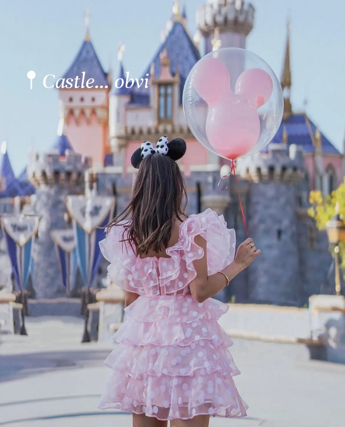  A little girl wearing a pink dress is holding a red balloon.