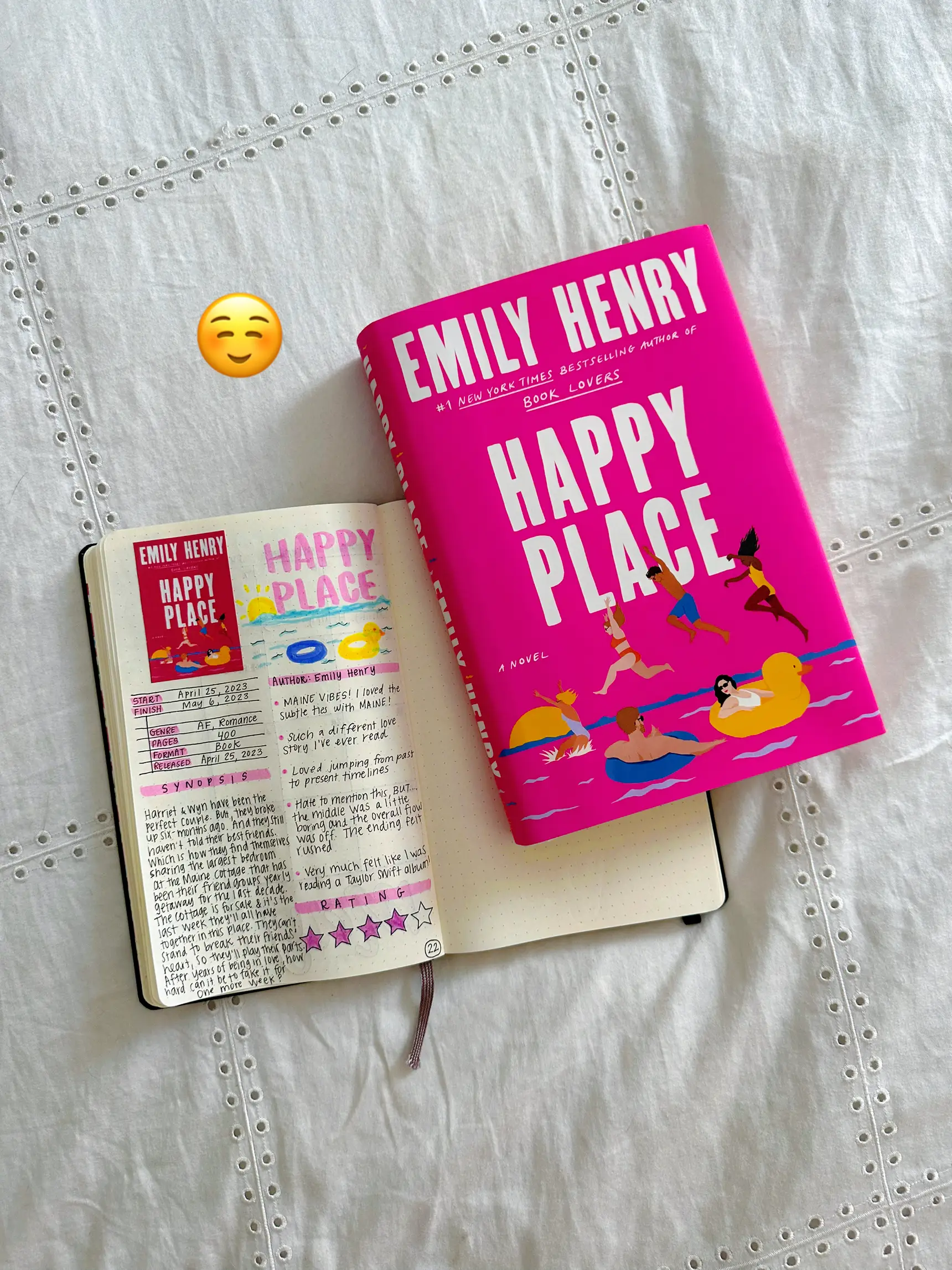  A book titled "Happy Place" by Emily Henry is sitting on a table next to a book titled "Emily Henry".