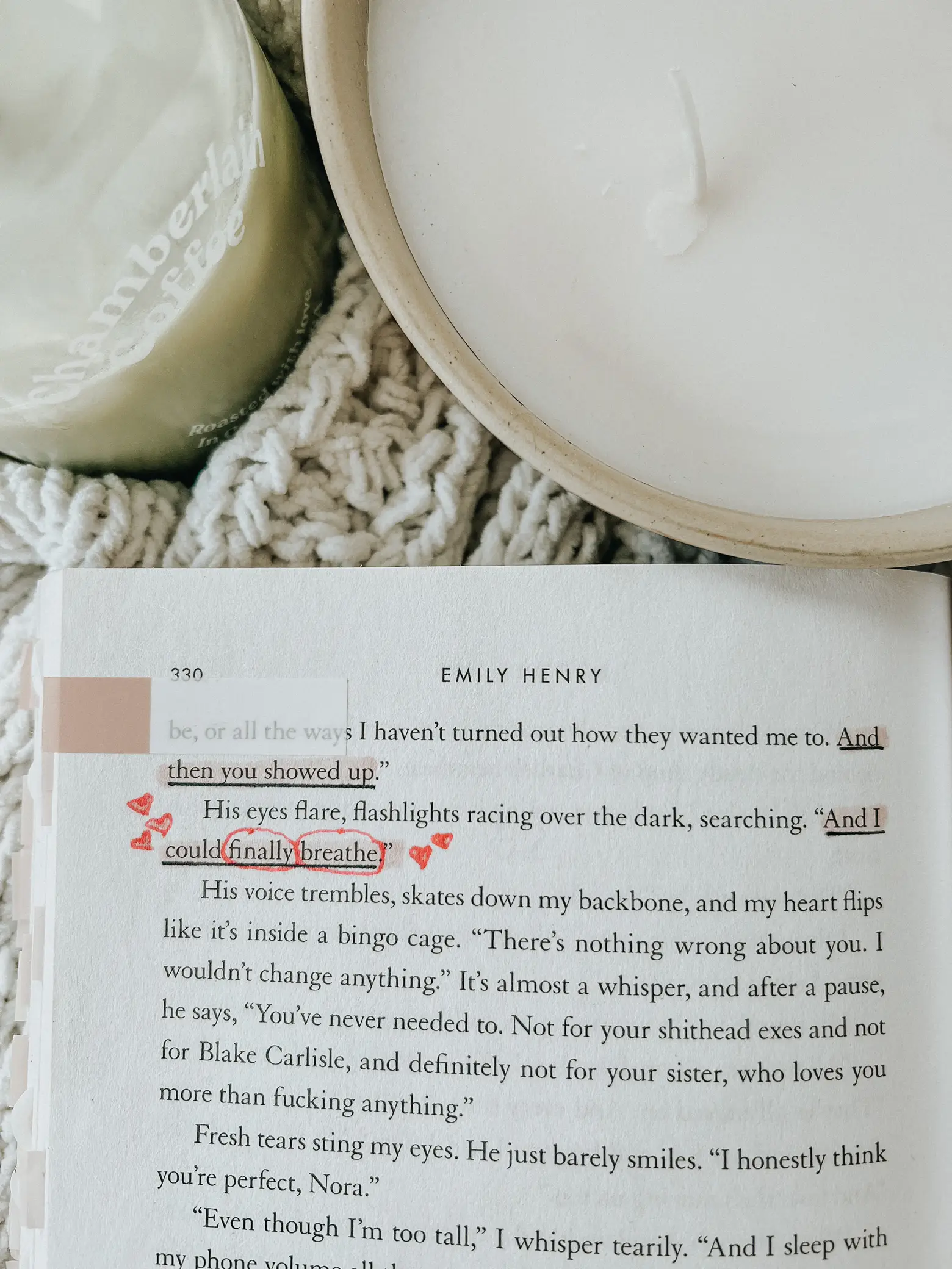  A book is open to a page with a red marker pointing to a passage. The passage is about Emily Henry.