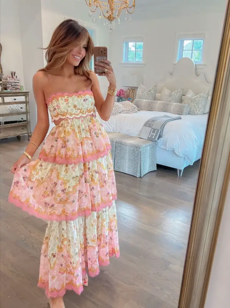  A woman wearing a floral dress is taking a selfie in a mirror.