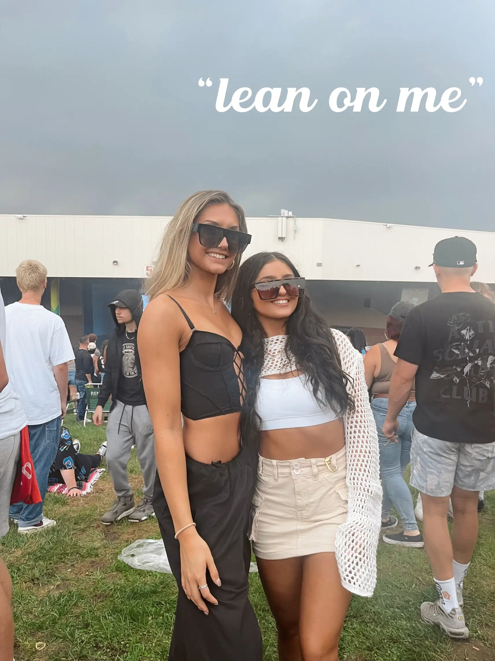  Two women are standing next to each other, posing for a picture. They are wearing shorts and sunglasses. The words "lean on me" are written above them.