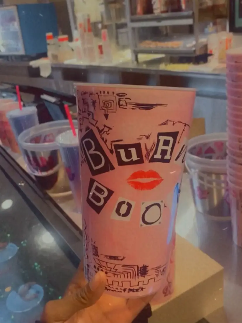  A hand holding a cup with the words "Buzz" and a woman's face on it.