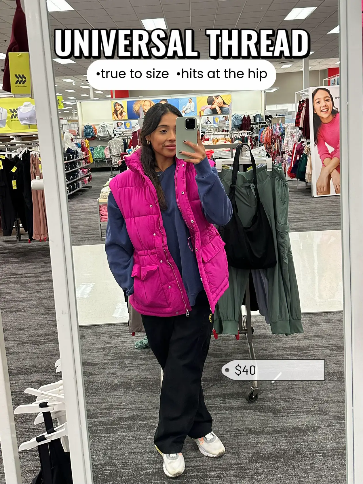  A woman in a pink jacket is taking a selfie in a mirror.