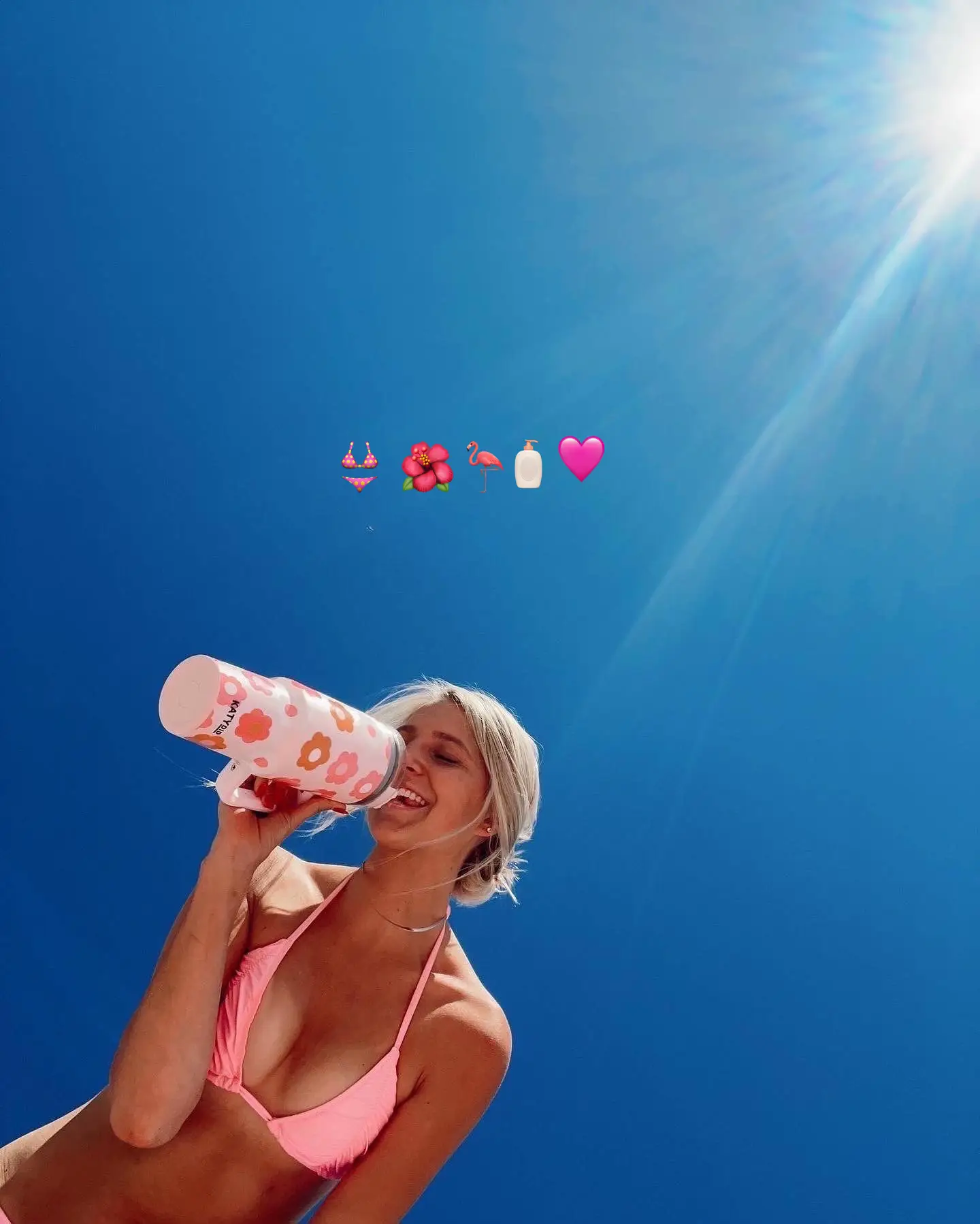  A woman in a pink bikini is drinking from a cup.