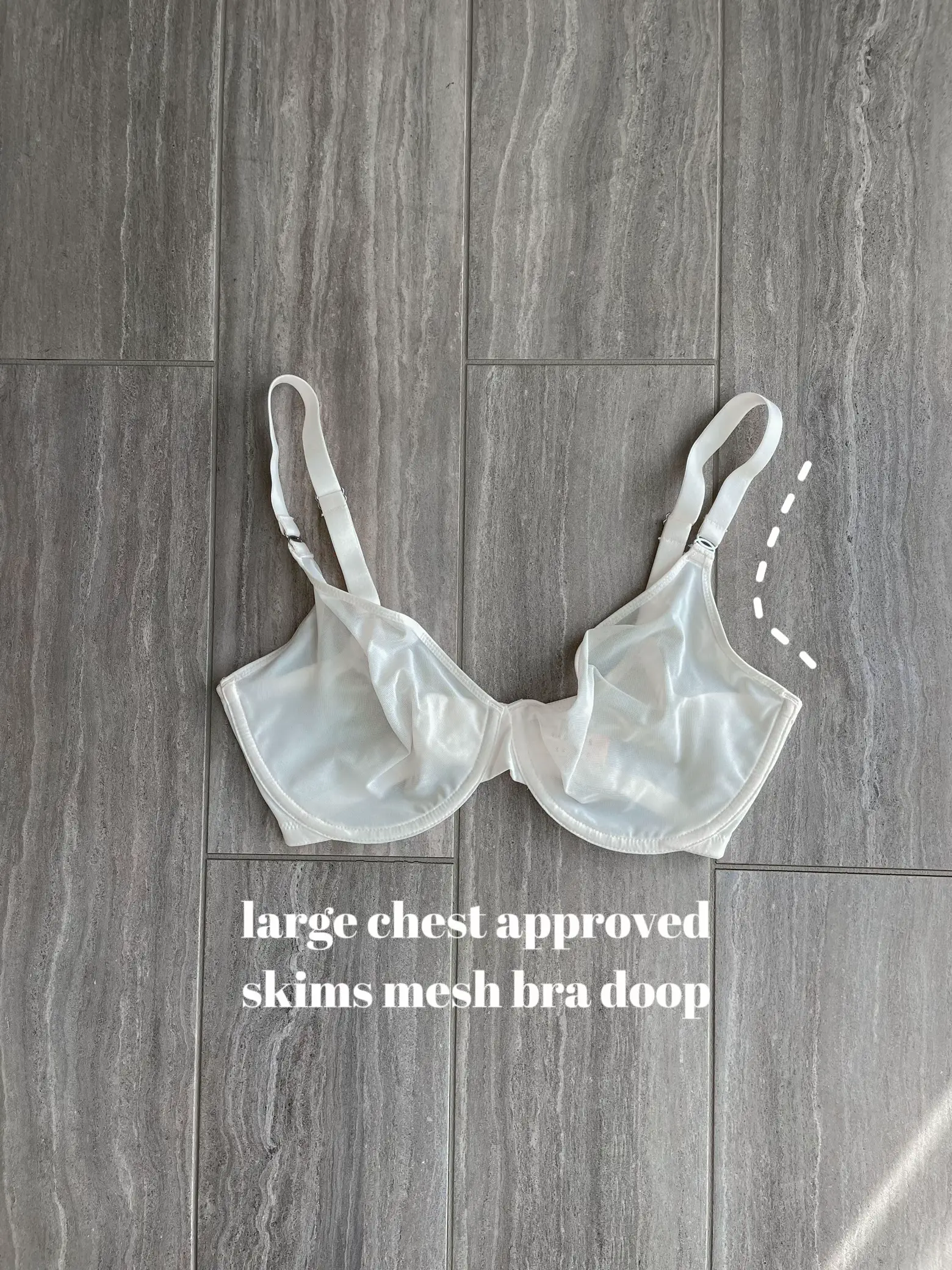  A white image of a bra with a doop on it.