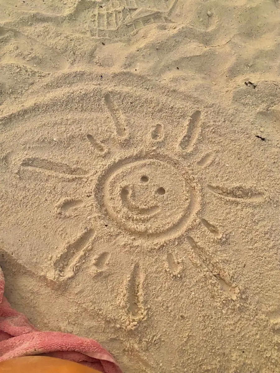  A child is playing on the beach with a sun dessin.