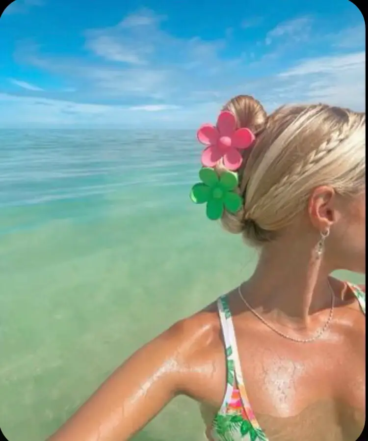  A woman wearing a bikini and a flowered shirt is standing in the water.