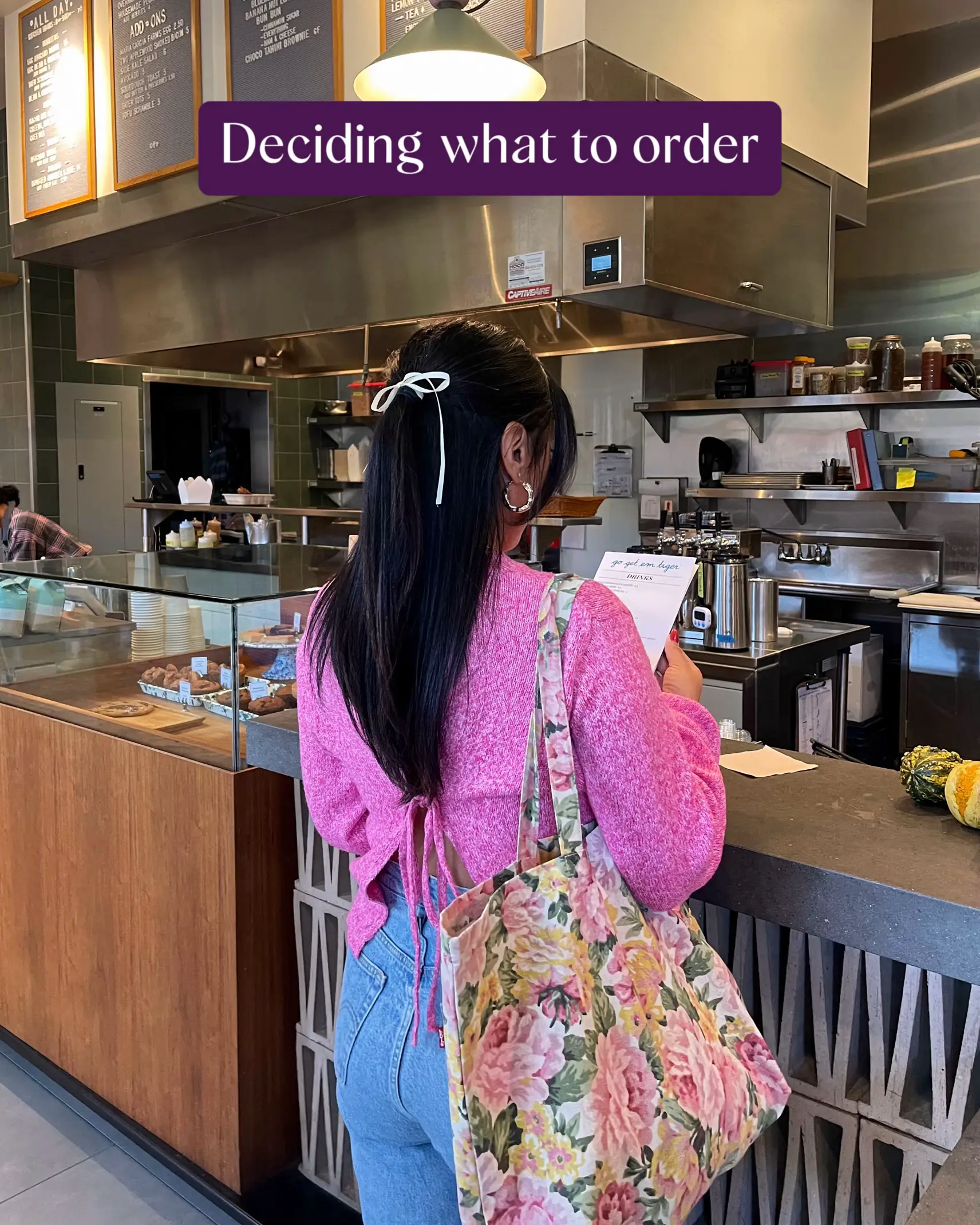  A woman is standing at a counter in a restaurant, looking at her menu.