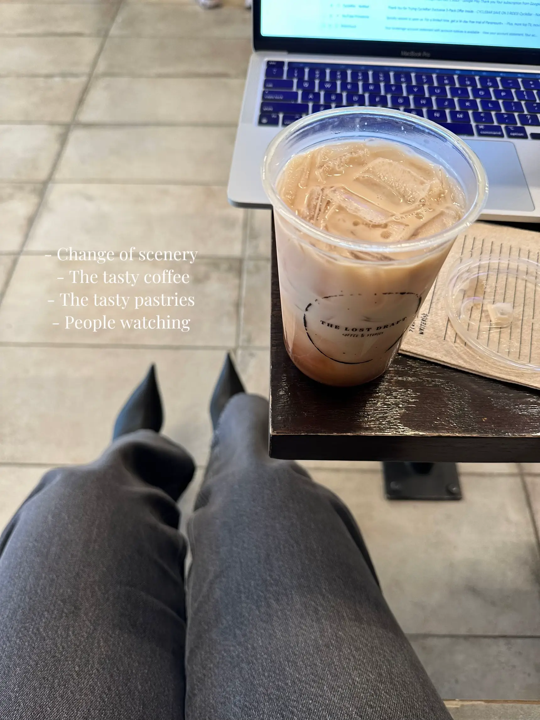  A person is sitting on a table with a cup of coffee and a pastry.