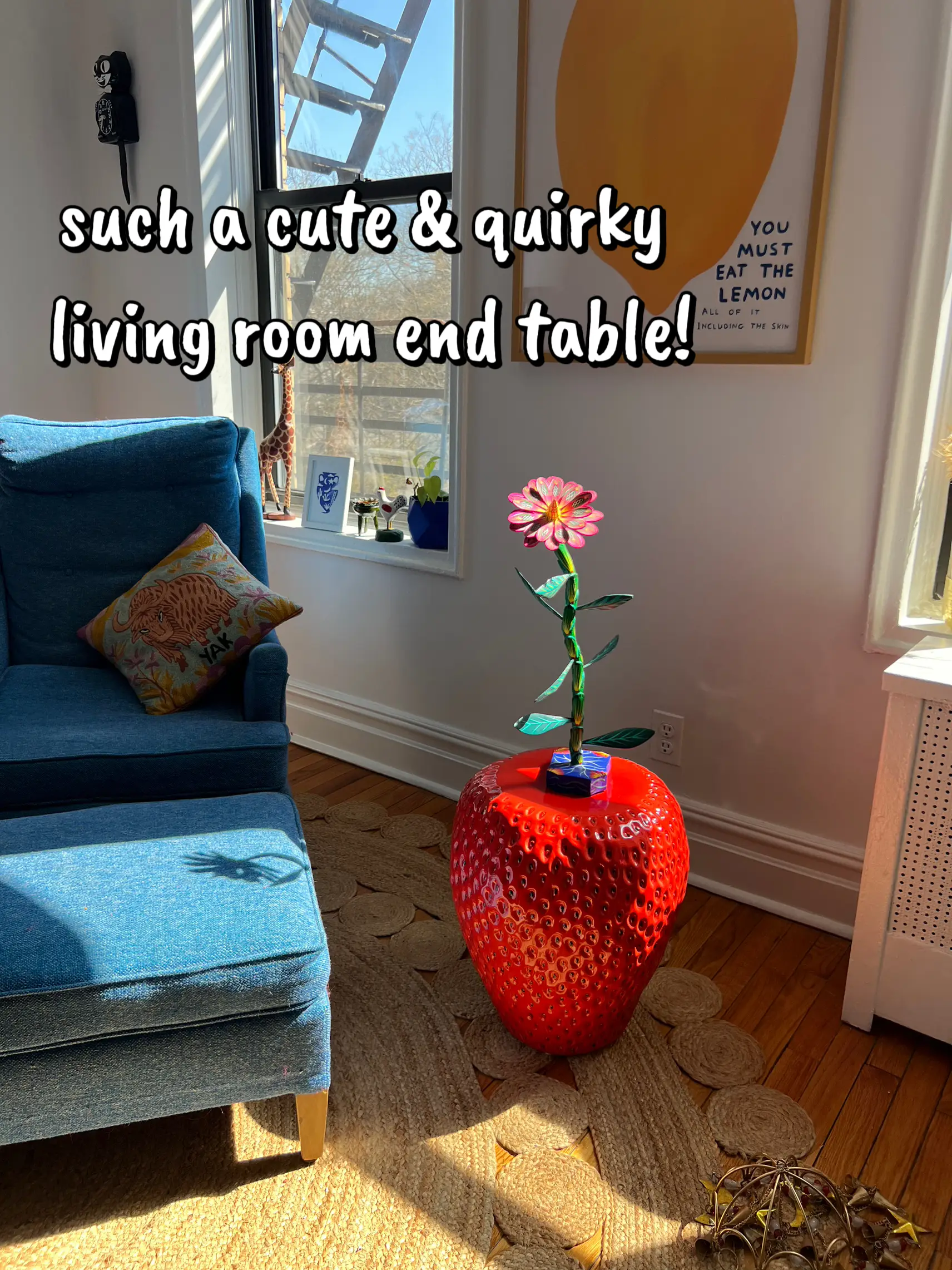  A red and white vase with a lemon on it is sitting on a table.