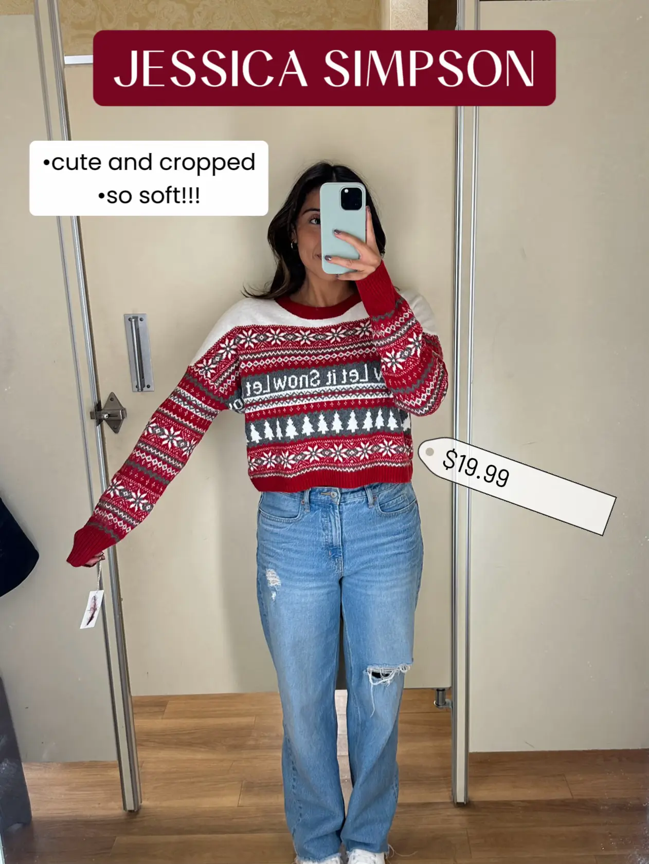  A woman in a red and white sweater is taking a selfie in a mirror.