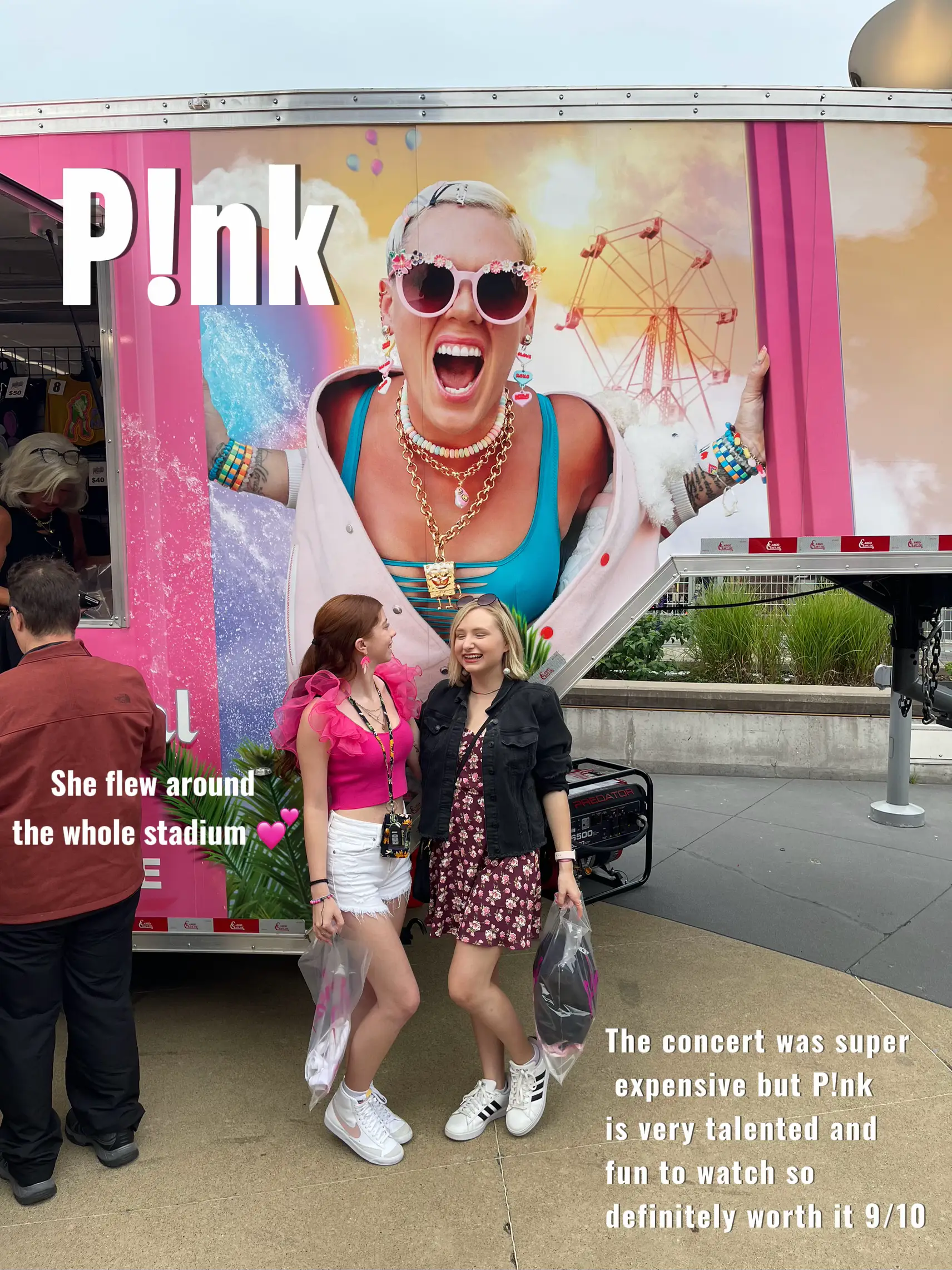  Two women are standing in front of a pink trailer with a picture of P!nk on it. They are posing for a picture and there is a sign that says "P!