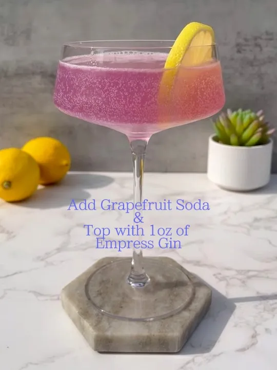  A glass of pink liquid with a grapefruit soda top.