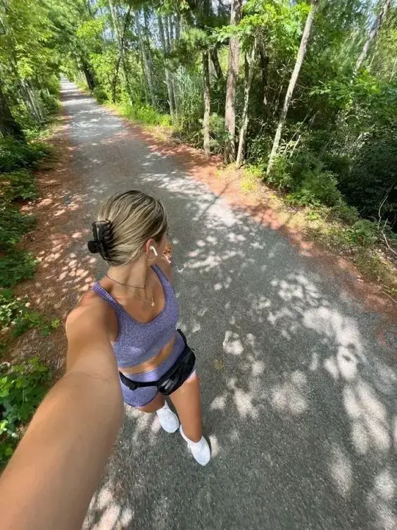  A woman wearing a black shirt and shorts is walking down a path.