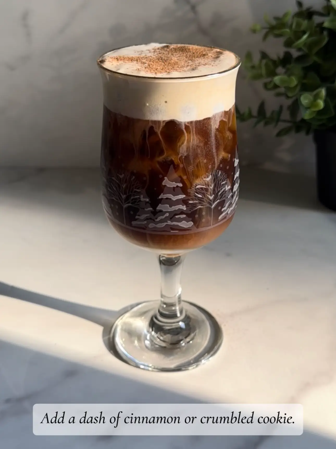  A glass of coffee with a cinnamon or crumbled cookie on top.