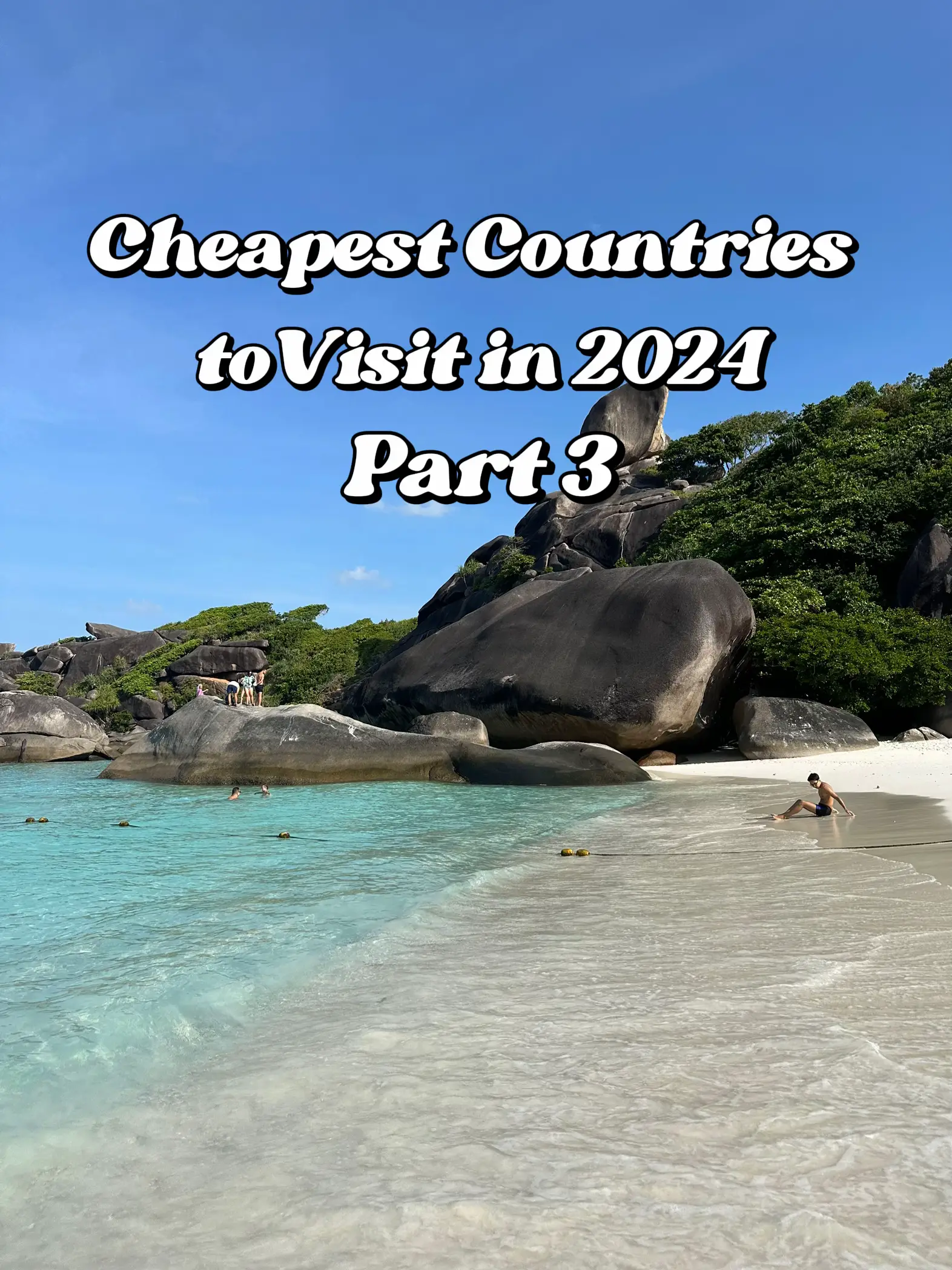  The image shows a beach with a rocky island in the background. The water is blue and clear, and there are several people enjoying the beach. The cheapest countries to visit in 2024