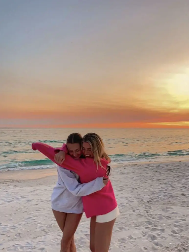  Two women are hugging each other on a beach.