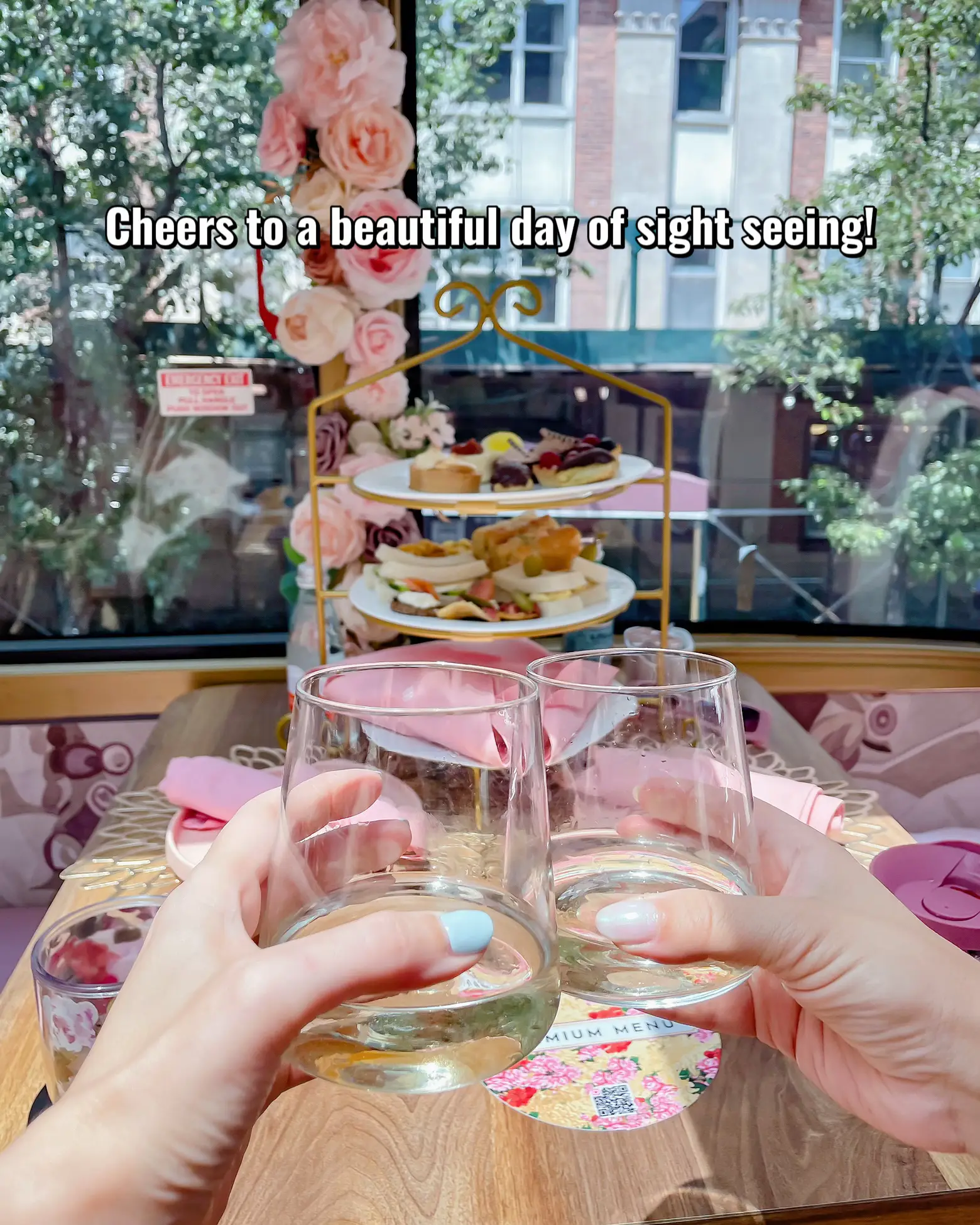  Two people are sitting at a table with a plate of food in front of them. They are holding wine glasses, and there is a potted plant nearby. The words "Cheers to a beautiful day