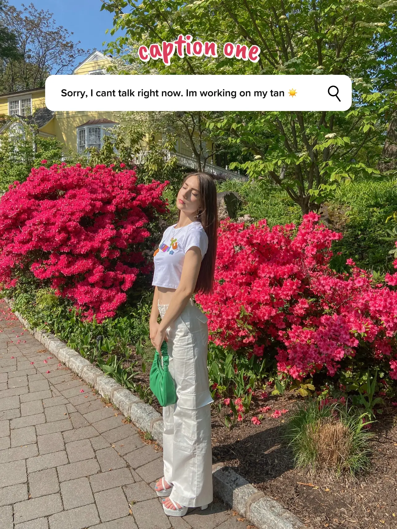  A woman in a white shirt and jeans is standing in front of a flower bed.