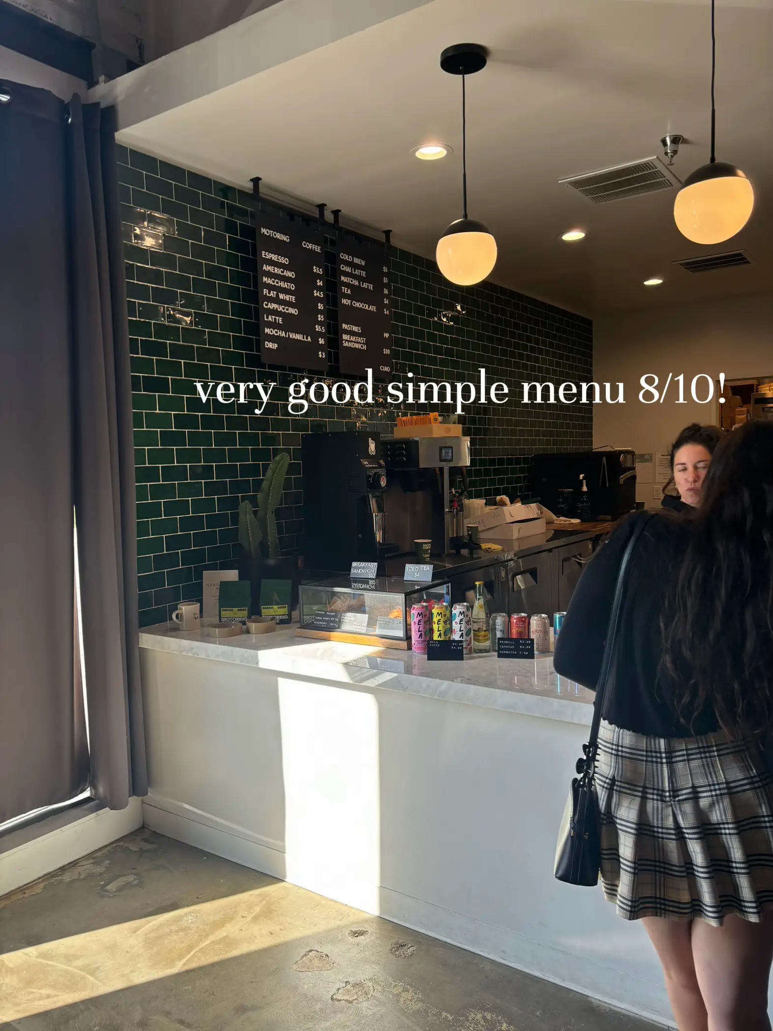  A woman is standing in front of a counter with a menu that says $10 very good simple menu.