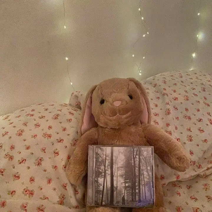  A stuffed animal, specifically a teddy bear, is holding a book with a picture of a tree on it.