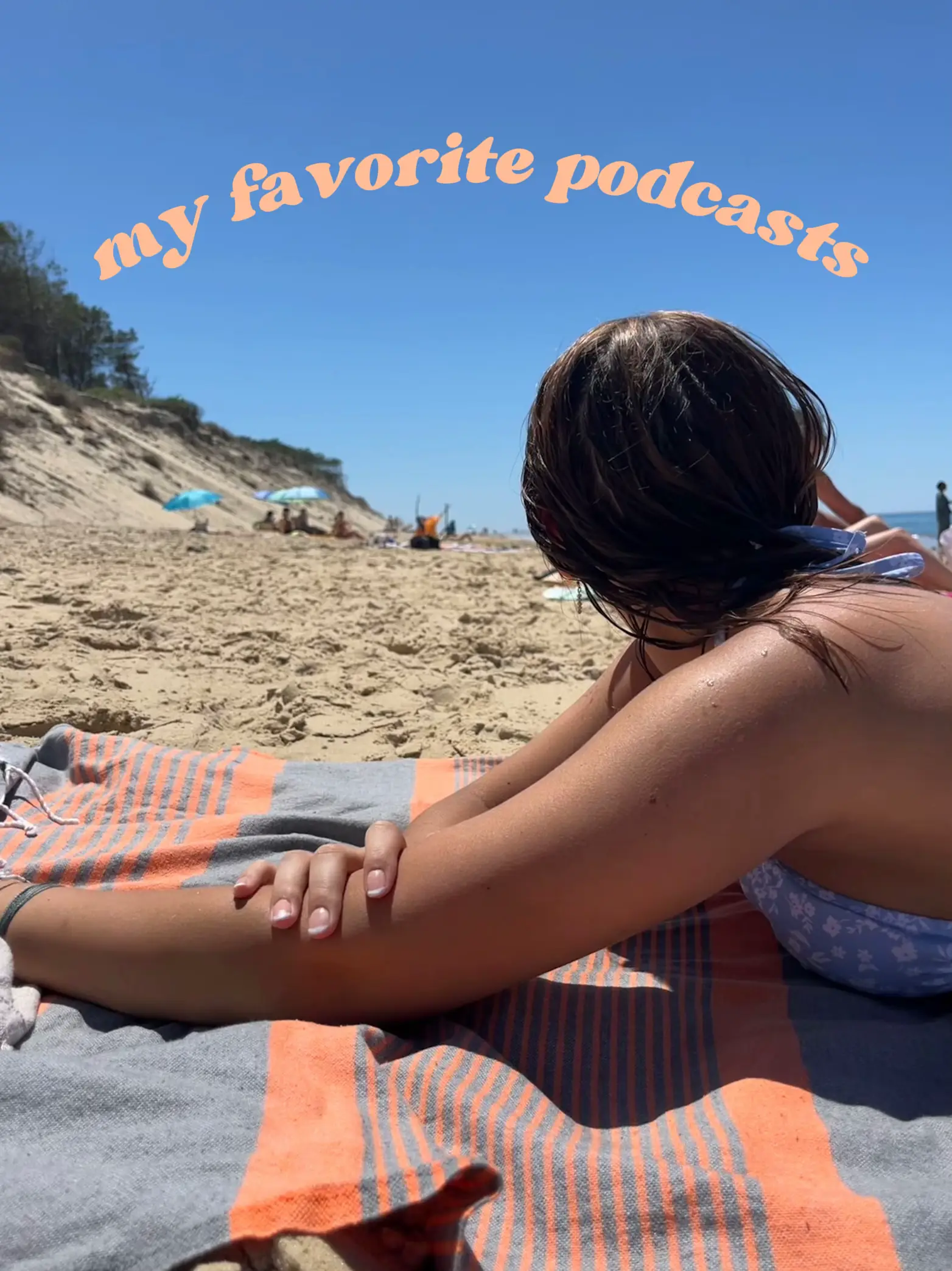 A woman is laying on a towel on the beach, listening to her favorite podcasts.