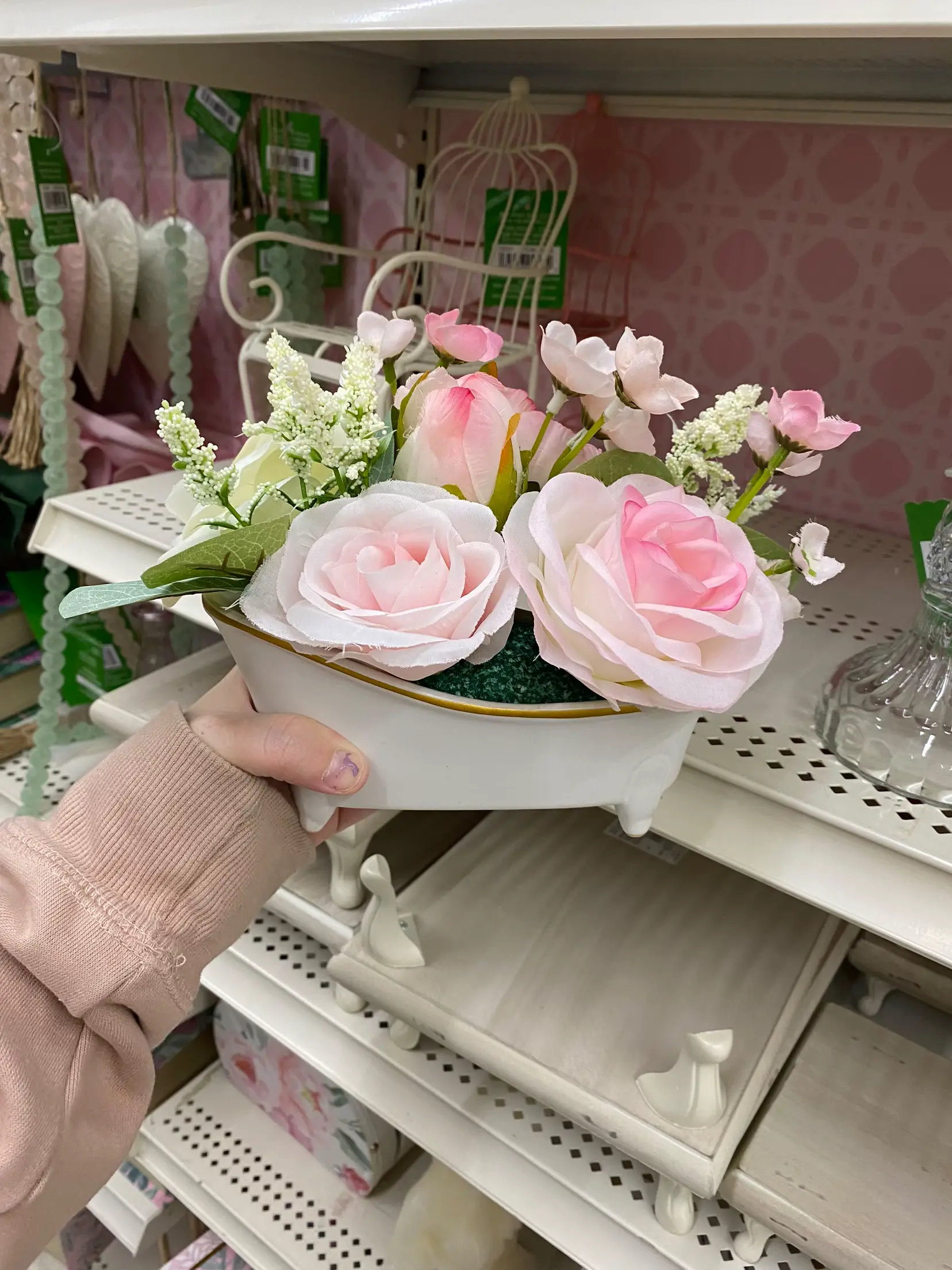  A hand holding a vase with pink flowers in it.