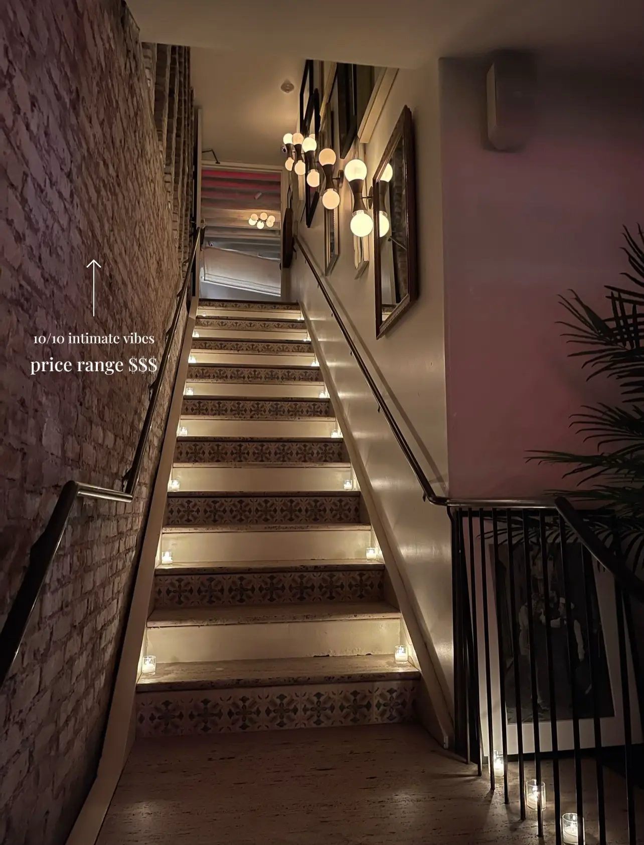  A staircase with a brick wall and a lighted railing.