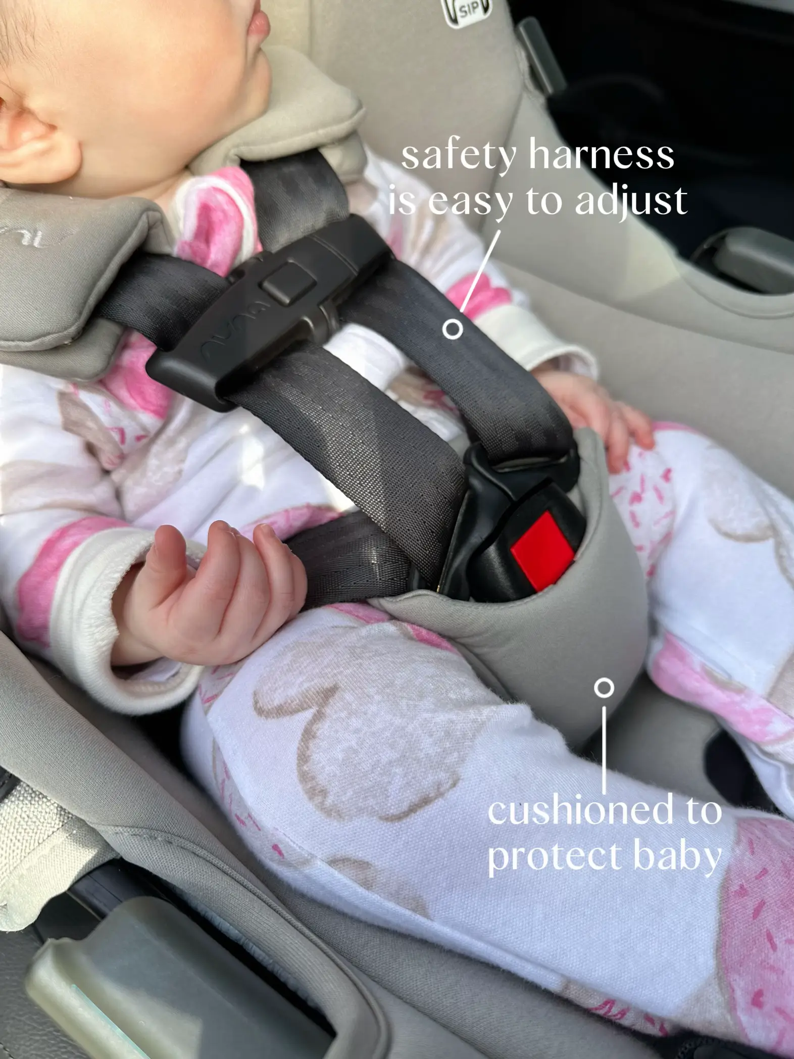  A baby is in a car seat with a safety harness and cushions.