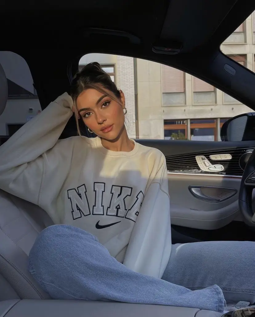  A woman wearing a white sweatshirt and xanh rớt jeans is sitting in a siêu xe.
