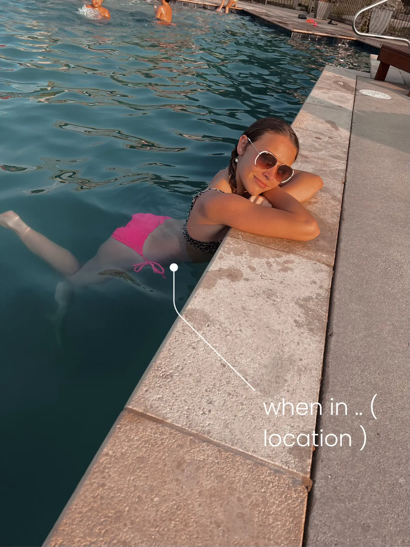 A woman in a bikini is laying on a ledge in a pool.