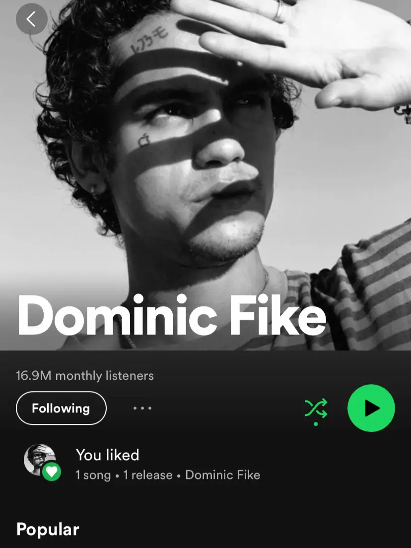  A man with a tattoo on his arm is listening to music on Spotify.